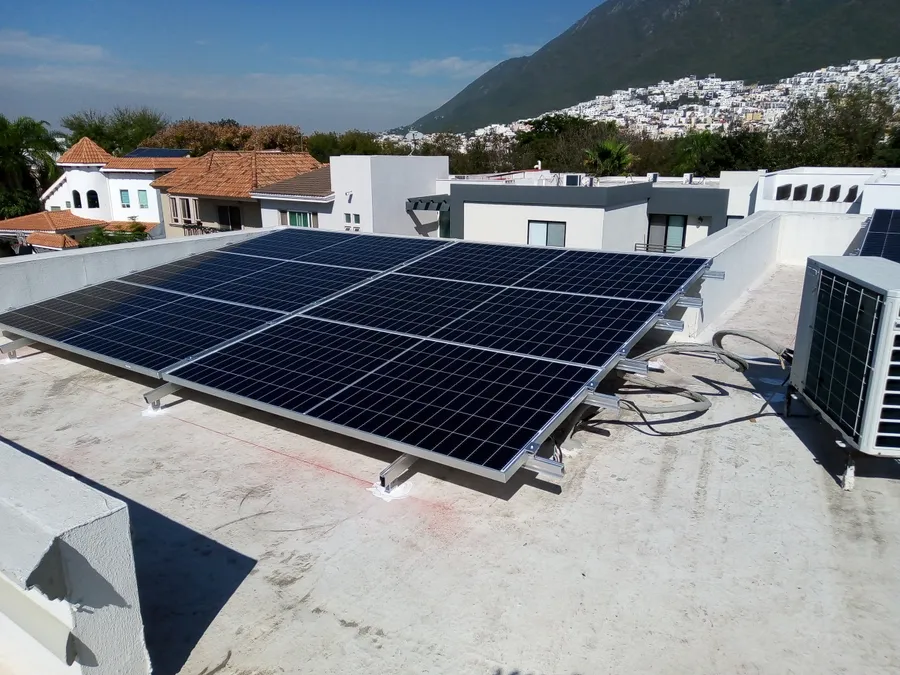 Paneles solares en la azotea de una casa con la montaña al fondo